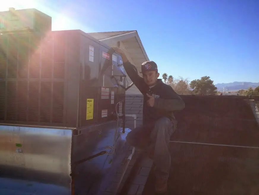 HVAC technician performing AC Tune-Up on a rooftop unit in Ecorse