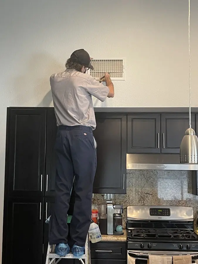 Technician inspecting an air vent during HVAC service in Ecorse